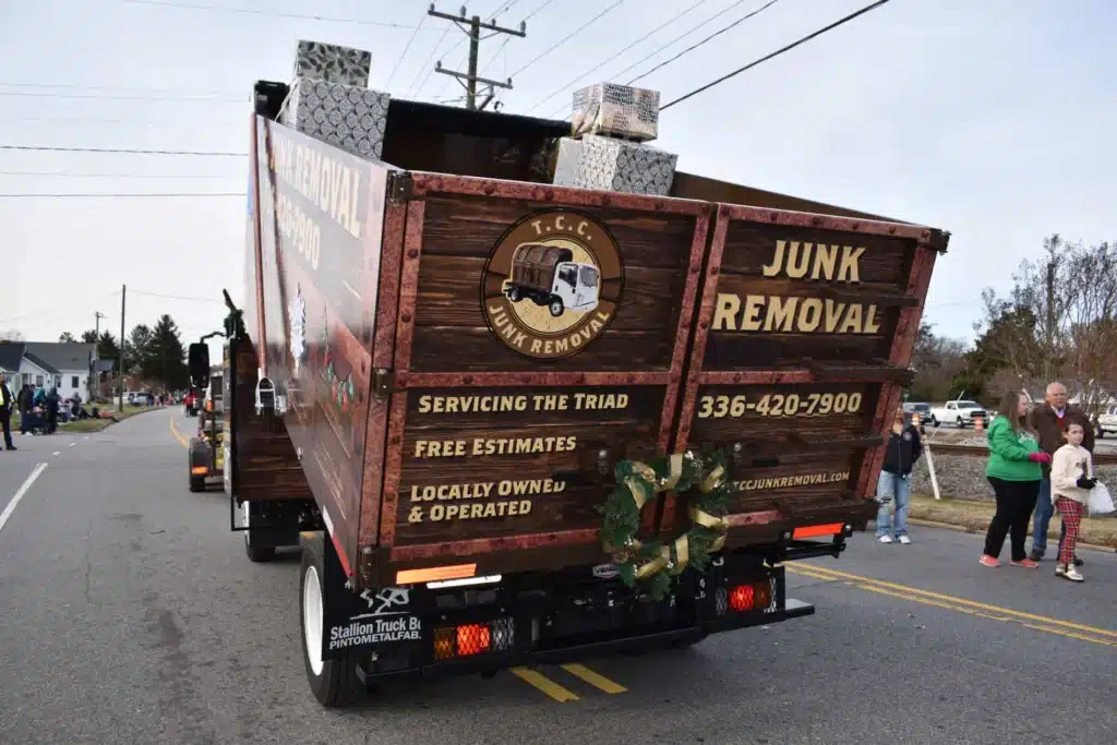 Junk removal truck with holiday decorations on street.