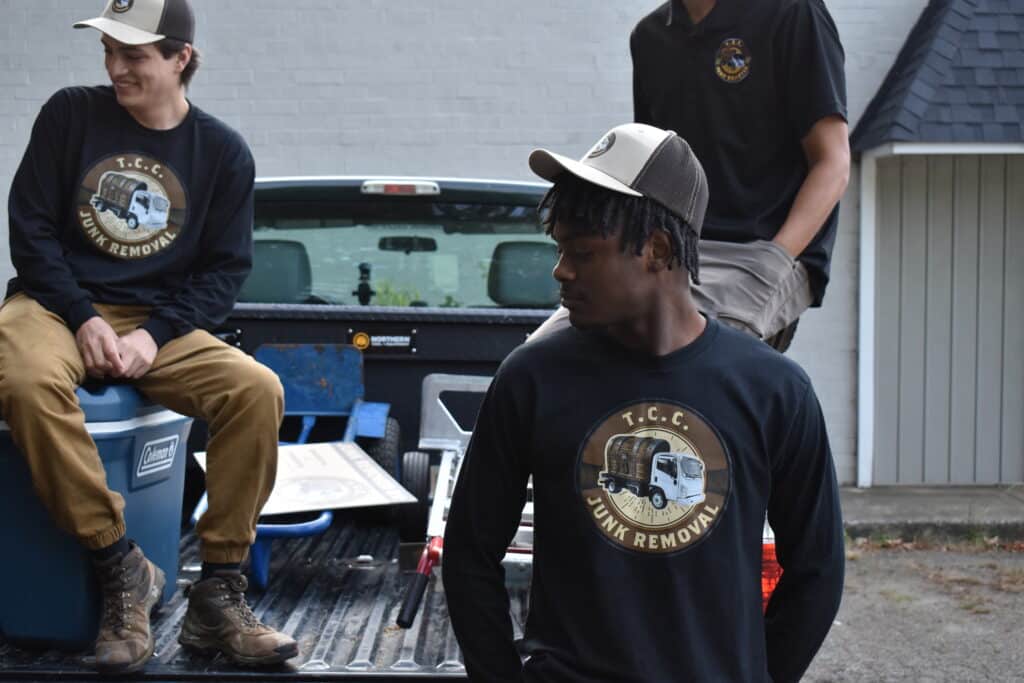 Team sitting on truck bed with company logo shirts.