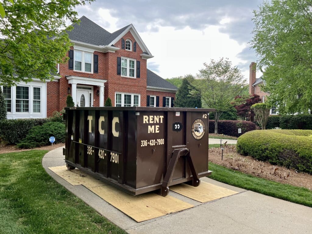 Dumpster on residential driveway, ready for rental.